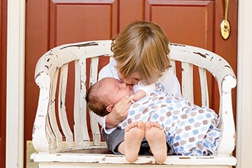 Little boy giving his baby sibling a kiss